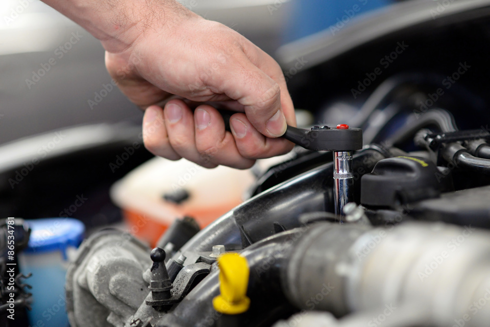 Mechaniker repariert auto in einer Werkstatt - Detail Hand mit Werkzeug  montiert im Motorraum // car repair in garage Stock Photo