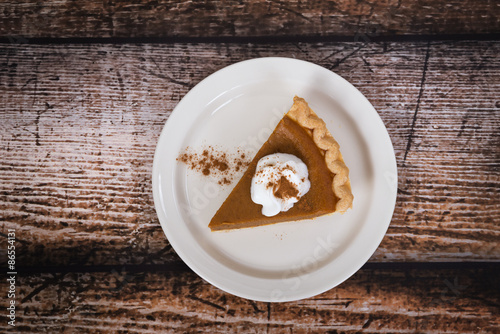 Slice of a pumpkin pie on wooden vintage table