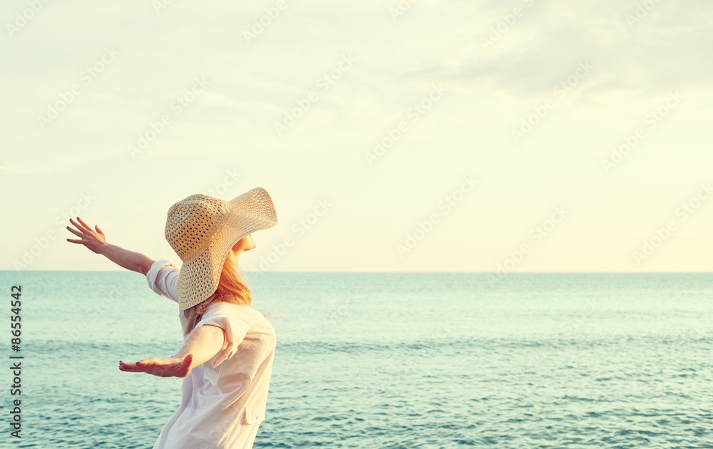 Naklejka premium Happy woman in hat is back opened his hands, enjoys sunset