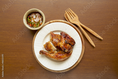 Grilled chicken with spicy sauce on wood background