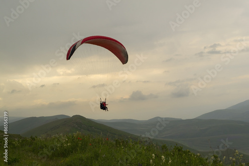 Paraglider tandem flight in mountains at sunset