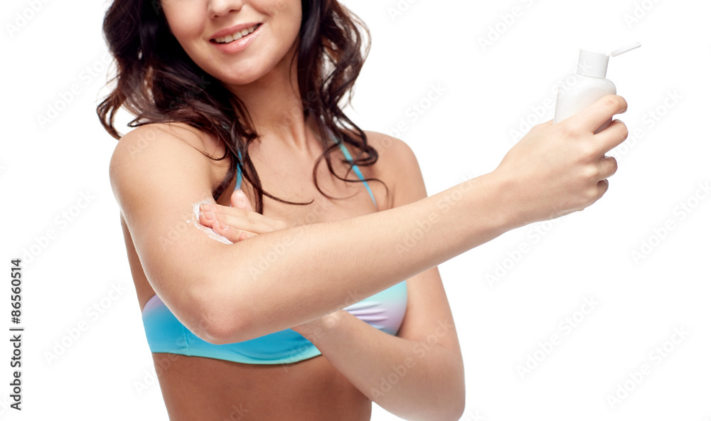 happy young woman in swimsuit applying sunscreen happy young woman in swimsuit applying sunscreen