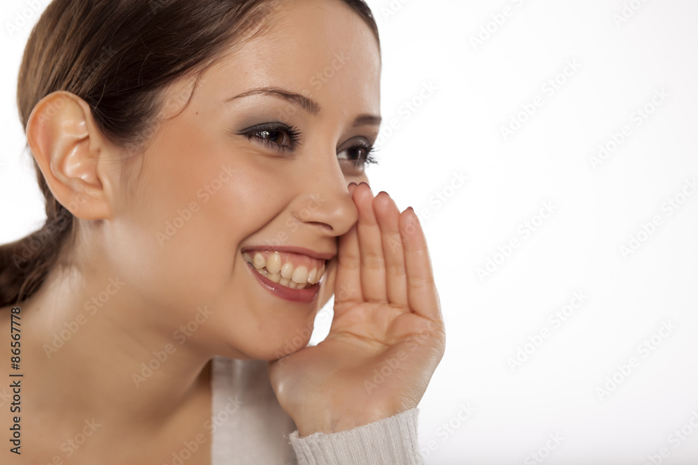 young woman holding her hand next to her mouth and whispers young woman holding her hand next to her mouth and whispers