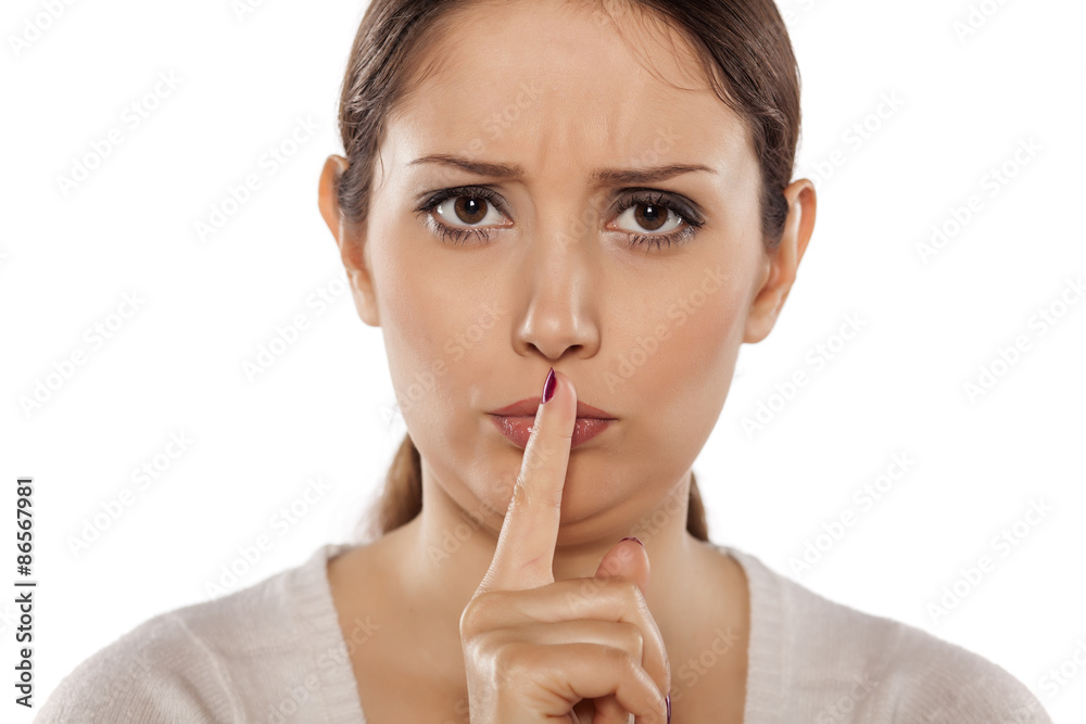 young woman holding a finger to her lips. concept for silence young woman holding a finger to her lips. concept for silence
