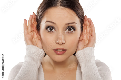 young woman carefully listening  with her hands behind the ears