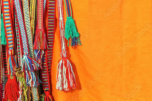 Colorful tassels of a hippie belts on orange background. photo