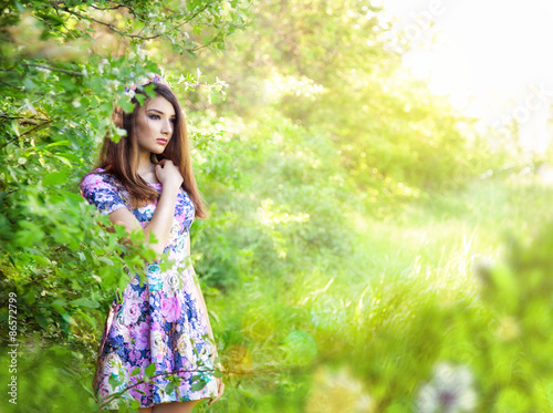Romantic portrait of young beautiful girl standing at summer par