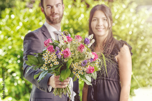Young Couple at the Garden with Bouquet of Flowers