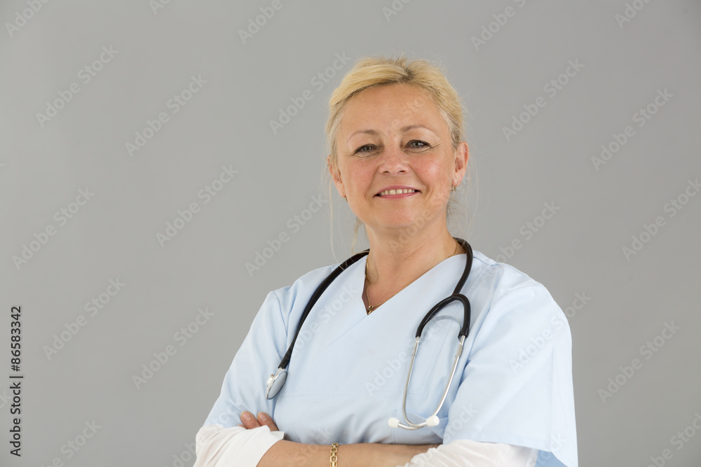 Close up portrait of blond female self confident doctor with crossed arms smiling and looking at the camera Close up portrait of blond female self confident doctor with crossed arms smiling and looking at the camera