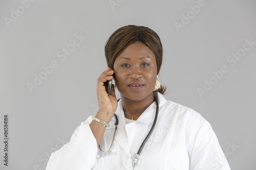 Black female doctor talking on cell phone and looking to the camera