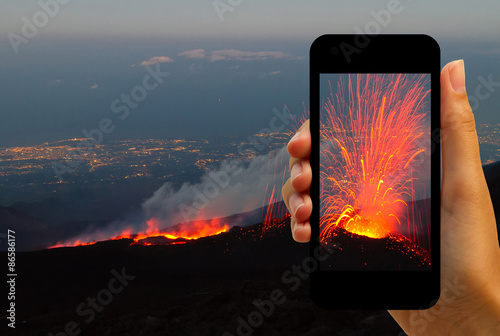 Tourist photographing the volcano eruption on smartphones 