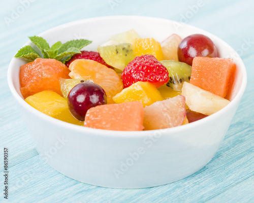 Fruit Salad - Bowl of fresh fruit salad on a blue background.