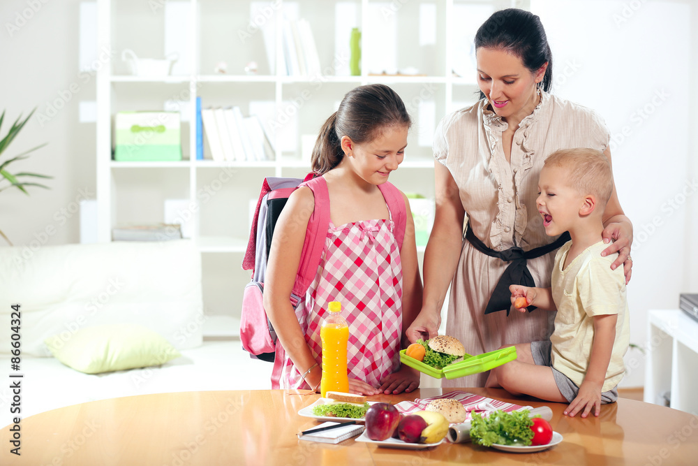 Mother making breakfast for her children in the morning and a snack for school Mother making breakfast for her children in the morning and a snack for school