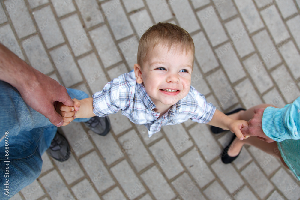 Naklejka premium Happy little boy holding fingers of father and mother