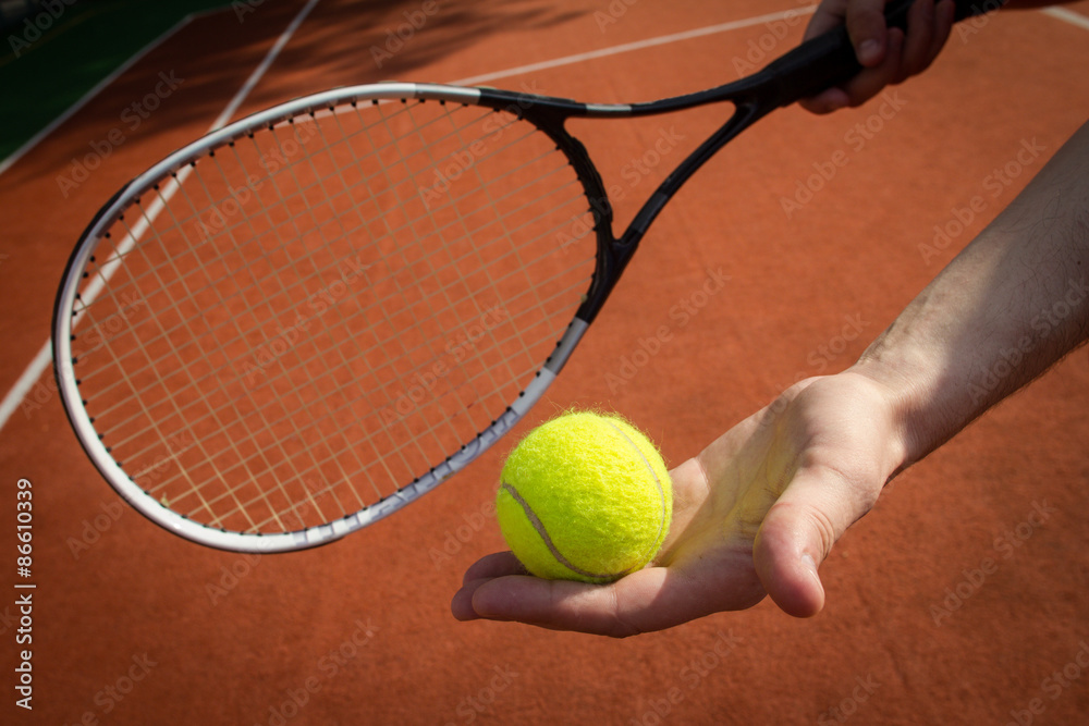 Hand holding tennis racket and ball on court