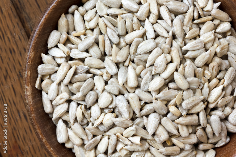 Shelled sunflower seeds in wood bowl isolated from above on rust Shelled sunflower seeds in wood bowl isolated from above on rust