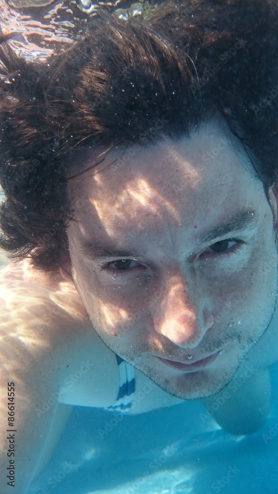Man in swimming pool underwater making selfie. Male diving under water from closeup portrait front view. Man in swimming pool underwater making selfie. Male diving under water from closeup portrait front view.