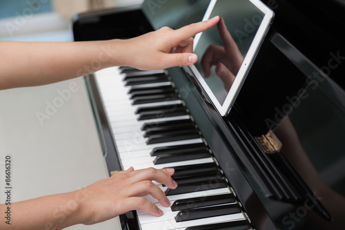 Woman hand use tablet and playing piano music