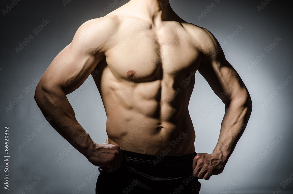 Muscular man posing in dark studio