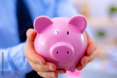 Businessman holding piggy box ,standing in office