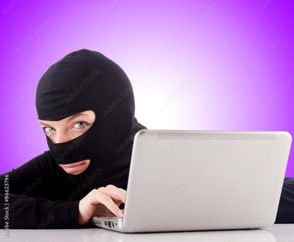 Hacker with computer wearing balaclava Hacker with computer wearing balaclava