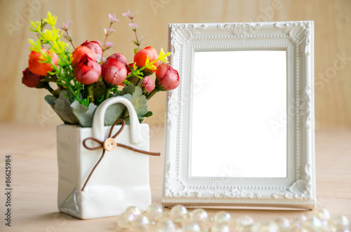 Flowers vase and vintage white picture frame.