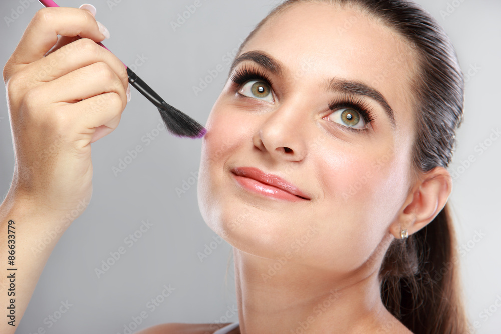 attractive model smiling while tidy up her make up