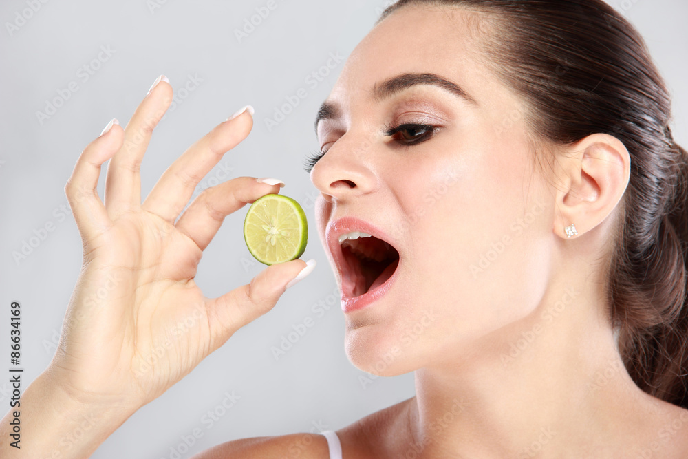 beautiful caucasian woman trying to eat a slice of lime beautiful caucasian woman trying to eat a slice of lime