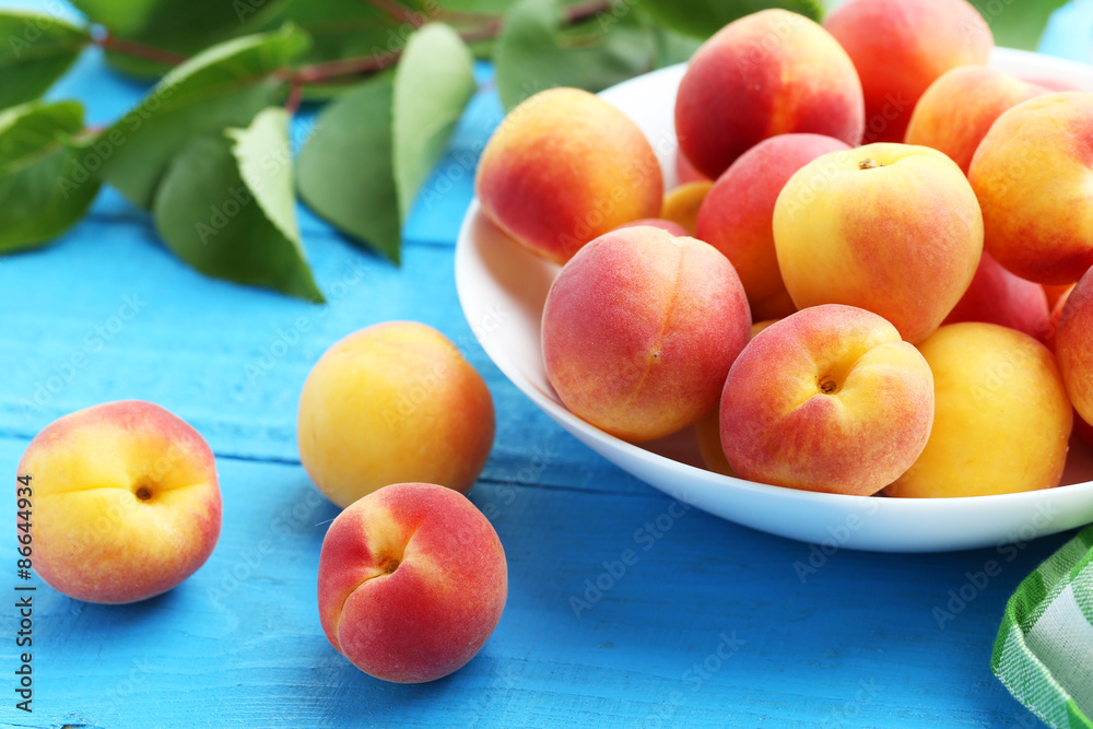 Fresh apricots in plate on a blue wooden background Fresh apricots in plate on a blue wooden background