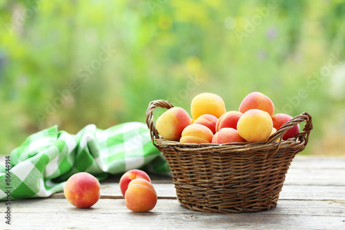 Fresh apricots in basket on a grey wooden background, ourdoors