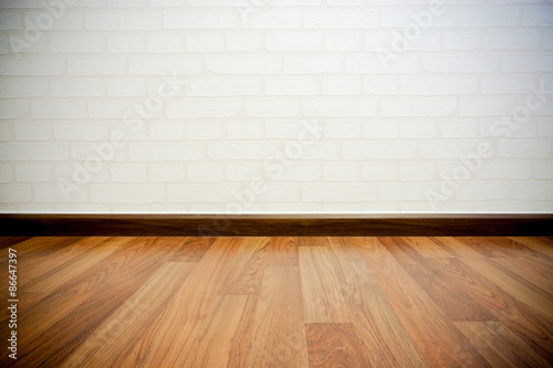 Copyspace background with an empty white bricks wall with a hardwood wooden floor below with large copy space for your text or advertisement © ampcool