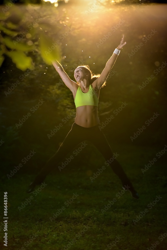 Woman jumping in forest at sunrise time