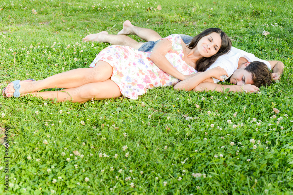 Happy loving pretty young couple outdoors having fun on the sunny day on green grass Happy loving pretty young couple outdoors having fun on the sunny day on green grass