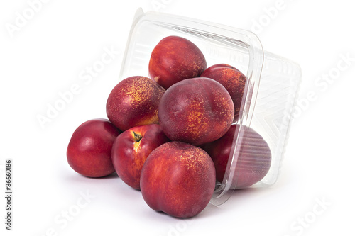 Konstfotografi Box or punnet and spilled fresh ripe organic nectarines isolated on white backgr