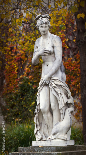 Mythological old classical statue with autumnal leaves in public park
