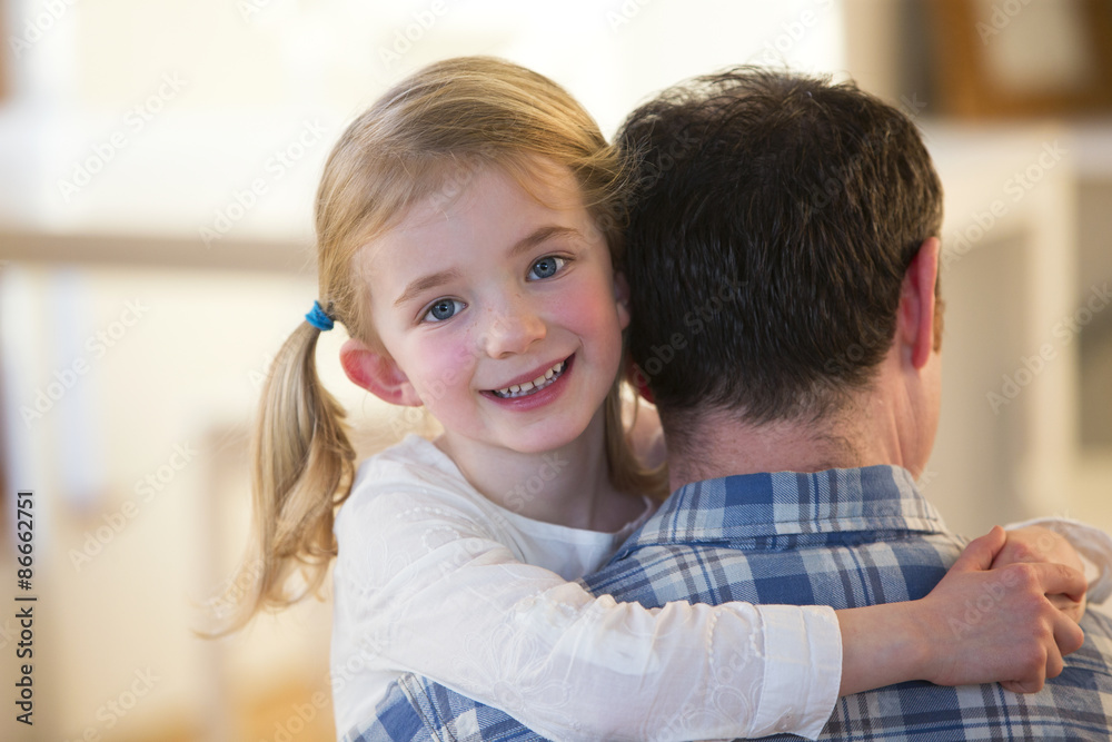 Little girl smiling over her fathers shoulder to the camera whilst hugging him Little girl smiling over her fathers shoulder to the camera whilst hugging him