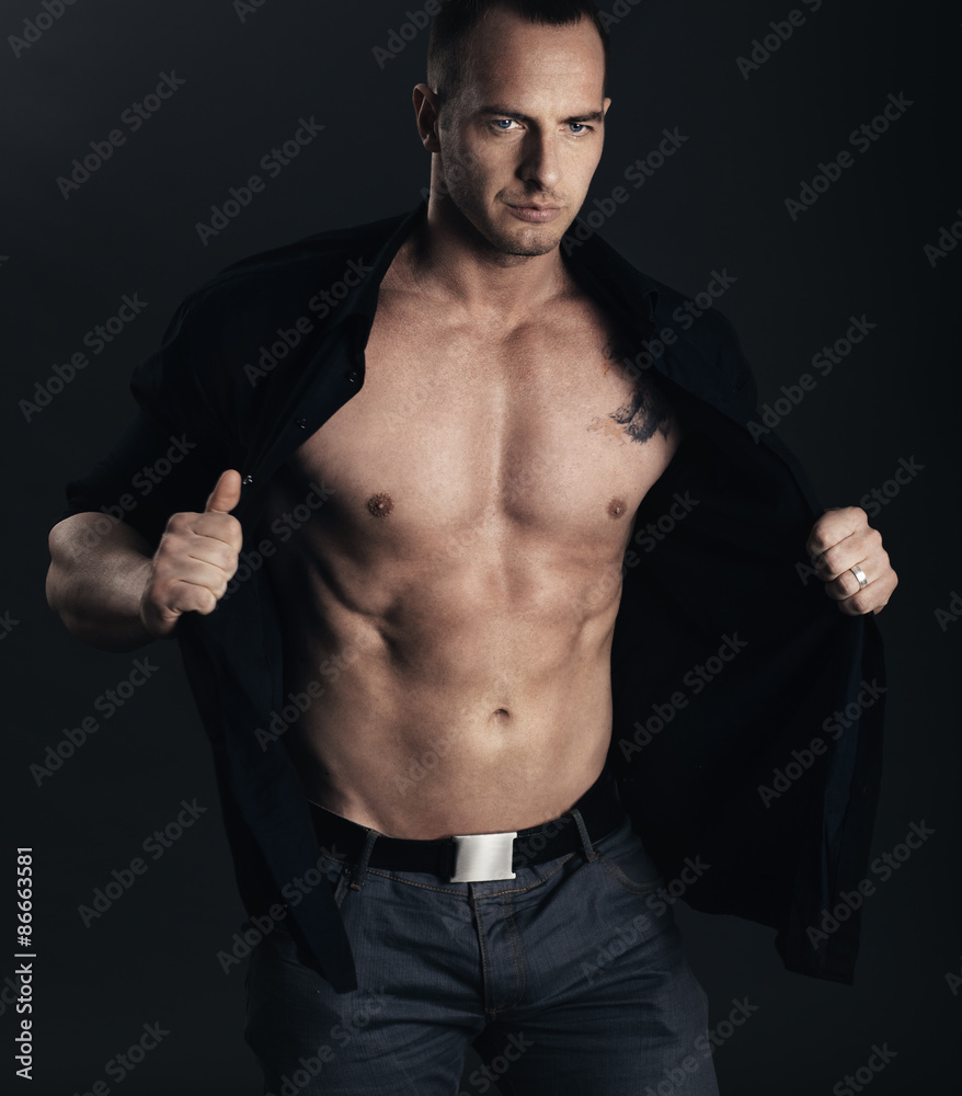 Fototapeta premium Man's style. Sexy man taking off his shirt. Studio shot.