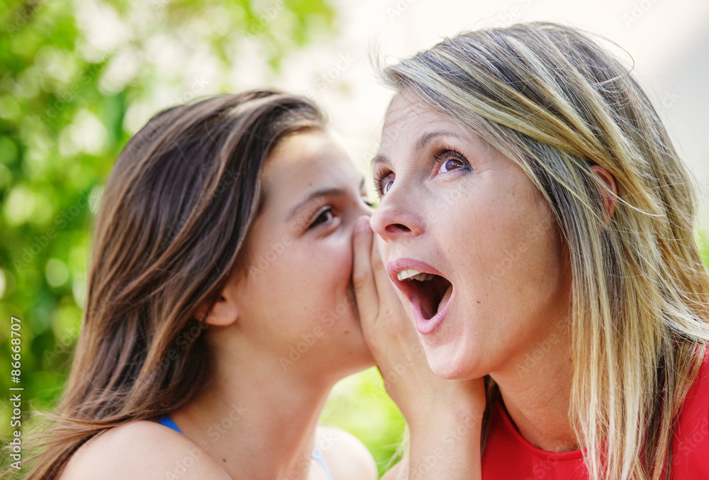 Teen whispering in the ear of her mother Teen whispering in the ear of her mother