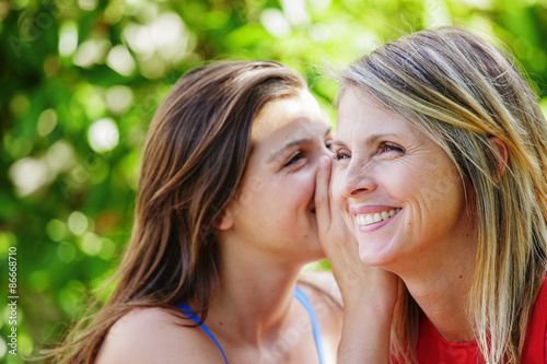 Teen whispering in the ear of her mother
