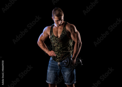 Handsome muscular bodybuilder posing over black background.