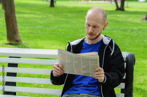 Young man reads on a bench in park