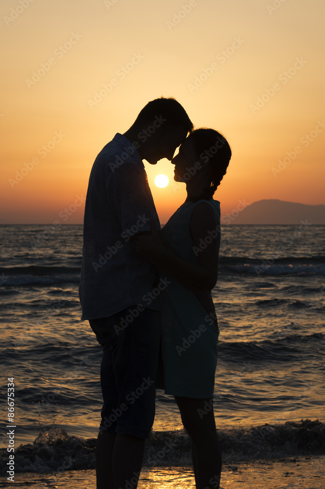 man and woman standing at sunset and looking at each other on se