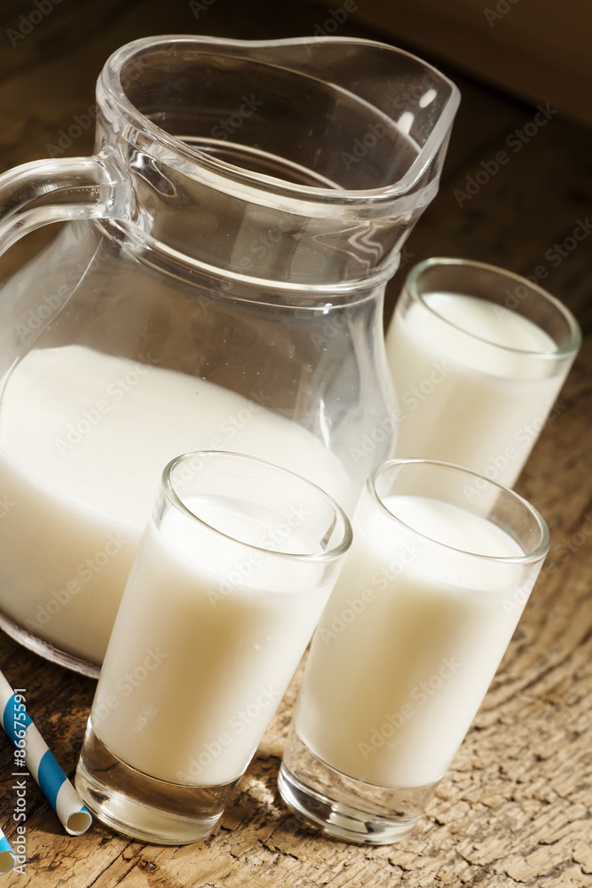 Jug of milk on old wooden table in rustic style, selective focus Jug of milk on old wooden table in rustic style, selective focus