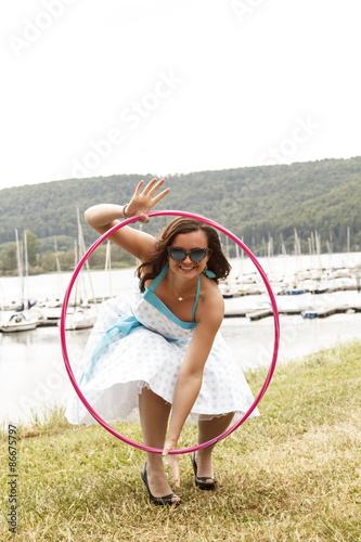 Frau in rosa Petticoat Kleid - gebückt mit Hulahoop-Reifen photo