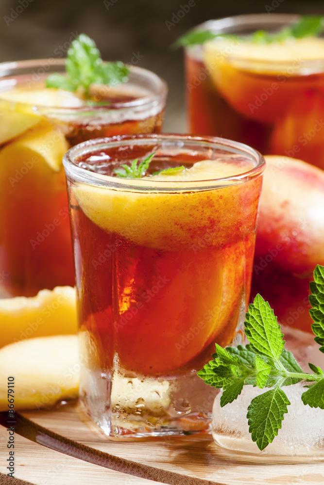Ice Peach Tea with pieces of fruit, ice and mint on a wooden boa Ice Peach Tea with pieces of fruit, ice and mint on a wooden boa