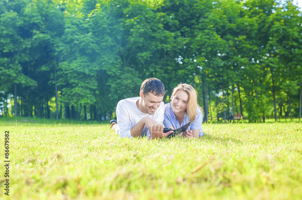 Happy Caucasian Couple in Love Lying on the Grass Outdoors. Read Happy Caucasian Couple in Love Lying on the Grass Outdoors. Read