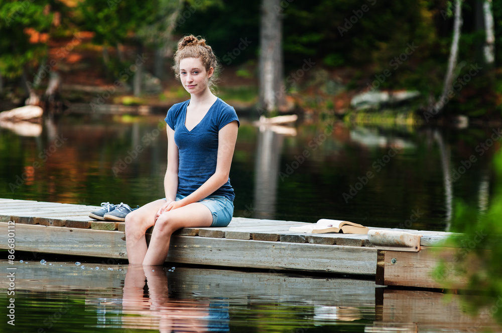 teenage girl sitting on a dock with her feet in the water Stock Photo ...