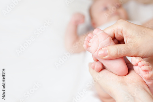 Mother makes massage for happy baby, apply oil on the foot, with white background and large copy space for any text
