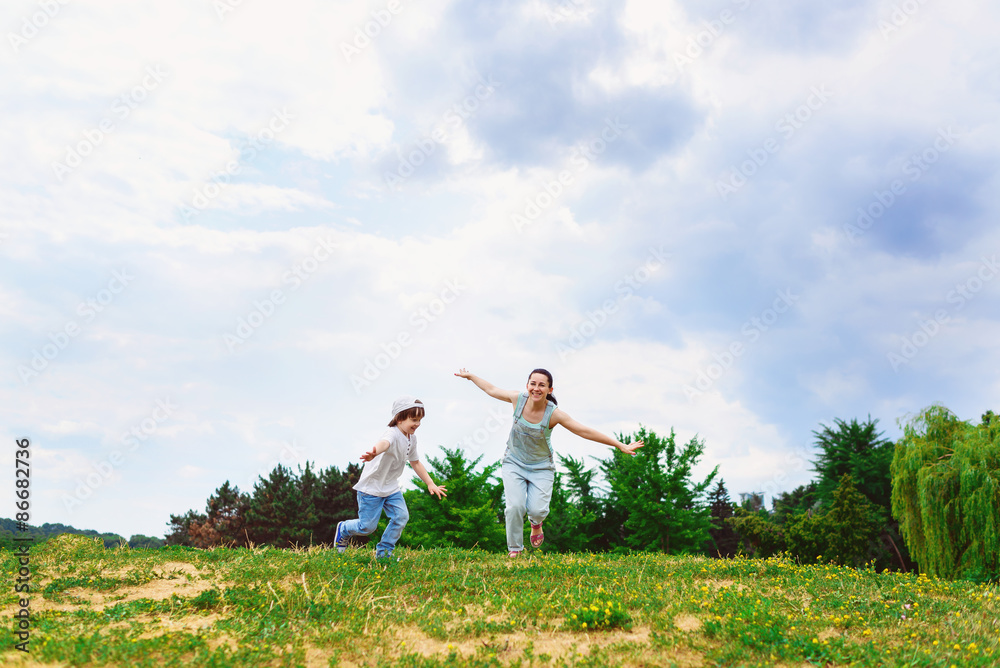 Happy Mother and son running on grass smiling Happy Mother and son running on grass smiling