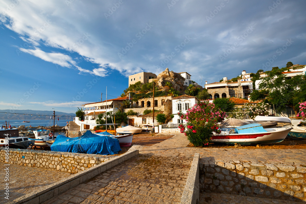 Dry river bed and boats in a fishing harbour in the town of Hydra.